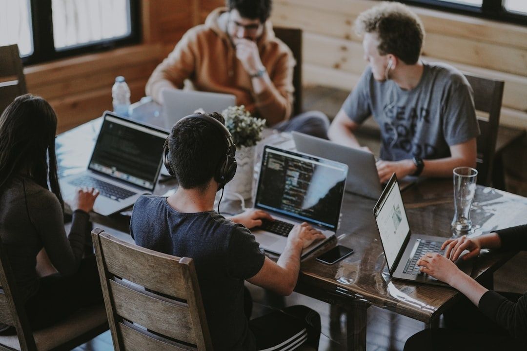 Teamleden werken samen aan laptops rond een tafel