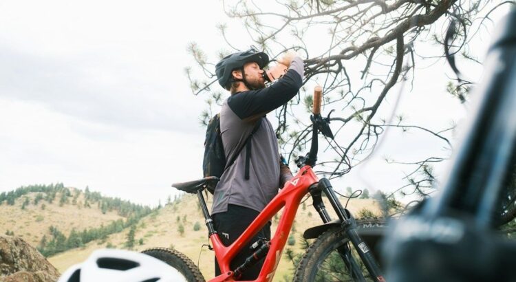 Mountainbiker drinkt uit een fles tijdens een rit in de bergen